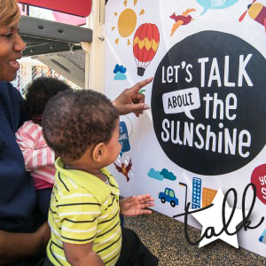 young family looking at Let's Talk poster
